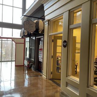 A view of a shopping area featuring modern storefronts and large windows, allowing natural light to illuminate the space.