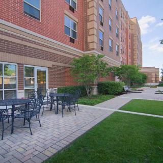 Outdoor patio area with tables and chairs next to a brick building.