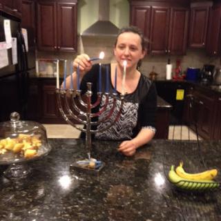 A person lighting the candles on a menorah during Hanukkah in a cozy kitchen.