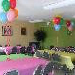 A festive room decorated with balloons and colorful tablecloths, ready for a celebration.