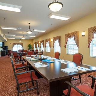 A well-lit conference room with a large meeting table and chairs arranged neatly, ready for a business meeting.