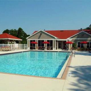 An outdoor swimming pool with a building featuring a red roof in the background.