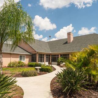 A charming house with a beautifully maintained garden and pathway under a partly cloudy sky.
