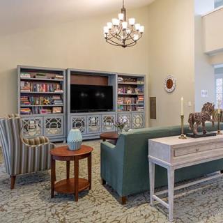 A stylish living room featuring a large bookshelf, a television, comfortable seating, and elegant decor.