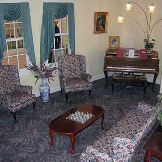 A cozy living room with patterned furniture, a piano, and elegant decor.