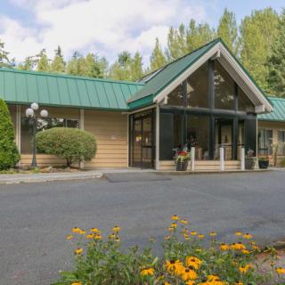 A modern building with a green roof surrounded by trees and flowers.