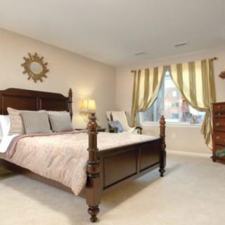 A cozy bedroom with a wooden bed frame, decorative pillows, and elegant drapery.