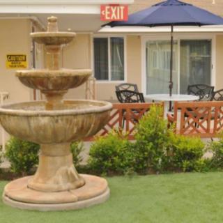 A serene outdoor patio area with a multi-tiered fountain and seating under an umbrella.
