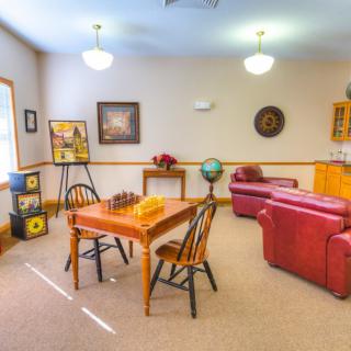 A cozy living room with a table and chairs, a red couch, artwork on the walls, and a globe for decoration.