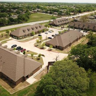 An aerial view of a suburban residential complex featuring multiple buildings and a parking area.