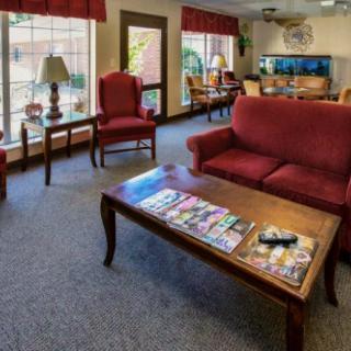 A cozy waiting room with red furniture and a coffee table topped with magazines.