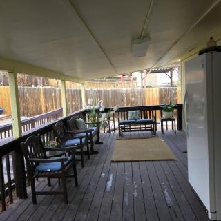 A cozy covered porch with wooden flooring and outdoor seating.