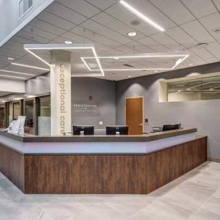 A modern office lobby featuring a sleek reception desk with minimalist design elements and contemporary lighting.