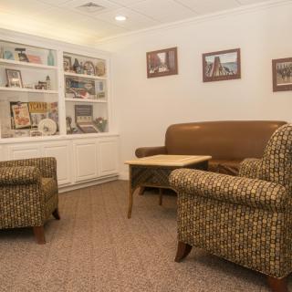 A cozy waiting room with comfortable seating and decorative shelves.