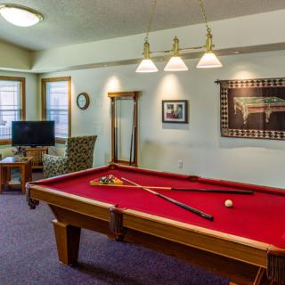 A cozy game room with a red-felt pool table and comfortable seating area.