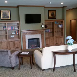 A cozy living room featuring sofas, a fireplace, and built-in bookshelves.