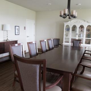 A spacious dining room with a long table, multiple chairs, and a decorative cabinet.