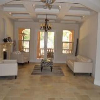 A spacious living room with elegant furnishings and multiple windows.