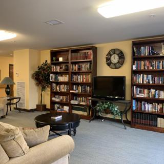 A cozy living room featuring bookshelves filled with books, a sofa, and a television.