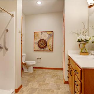 A well-lit and modern bathroom featuring a shower, toilet, and stylish vanity.