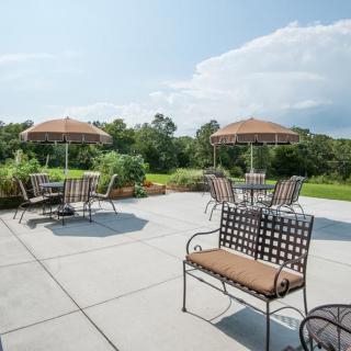 A sunny outdoor patio with tables, chairs, and umbrellas overlooking a lush landscape.