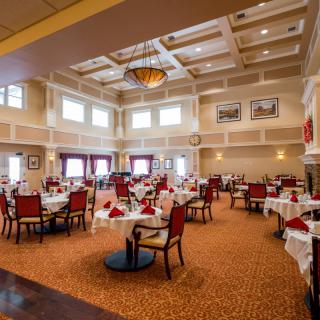An elegant restaurant dining area with neatly arranged tables and chairs, featuring a stylish ceiling design and chandelier.