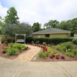 A beautifully landscaped garden with a winding pathway leading to a small building, surrounded by lush greenery and colorful plants.
