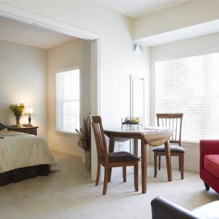 A cozy apartment interior featuring a bedroom, dining area, and living space.