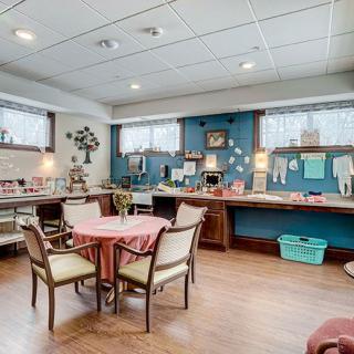 A cozy dining and kitchen area with a homely atmosphere, featuring a round table surrounded by chairs and decorated walls.