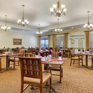 An elegant dining room setup with neatly arranged tables and chairs, adorned with chandeliers and a warm ambiance.