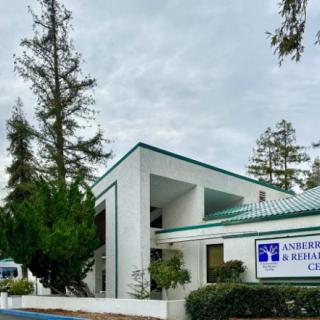 An office building with a modern design surrounded by trees under a cloudy sky.