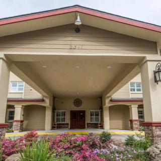 A well-maintained building entrance with a covered porch and vibrant flower landscaping.