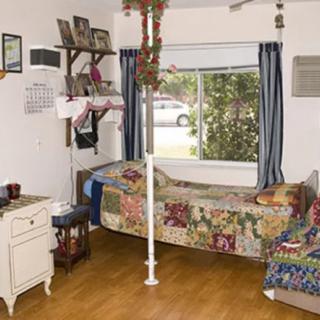 A cozy bedroom with a colorful quilt on the bed, decorated with various personal items and a view of the outside through the window.