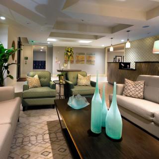 A modern living room with stylish decor featuring green and beige furniture, decorative vases on the coffee table, and elegant lighting.