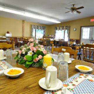 A dining room with tables set for a meal, featuring flowers and dishes on the table.