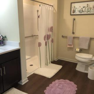 A neatly organized bathroom featuring a shower with a floral curtain, a toilet, and a vanity.