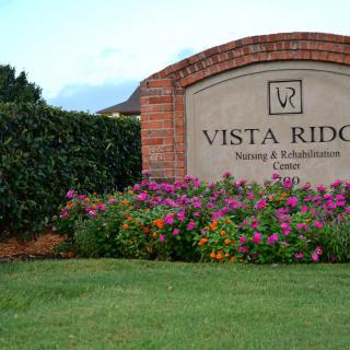 A sign for Vista Ridge Nursing & Rehabilitation Center surrounded by well-maintained landscaping and flowers.