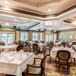 An elegantly furnished dining room with multiple tables set for a meal.