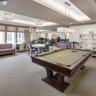 A recreation room featuring a billiards table and comfortable seating.