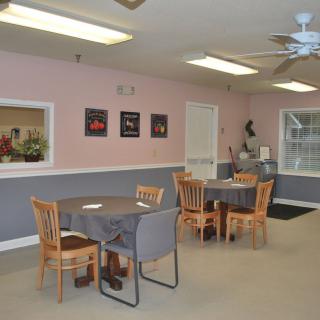 A small dining area with tables and chairs set up, featuring simple decor and ceiling lights.