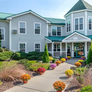 A well-maintained residential building with a green roof and a landscaped pathway adorned with colorful flowers.