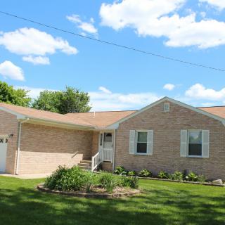 A single-story brick house with a well-maintained yard and garden.