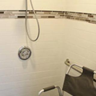An accessible bathroom with a shower chair and handheld showerhead.