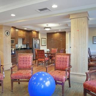 A communal dining and activity space with wooden chairs and an exercise ball.