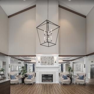 A modern living room with high ceilings, featuring a central fireplace and stylish chandelier.