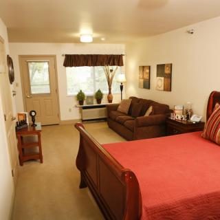 A cozy bedroom with a large bed and a sofa, featuring warm decor and natural light.