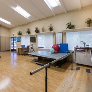 A rehabilitation therapy room equipped with exercise equipment and safety bars.