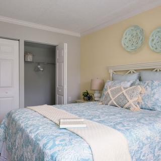 A cozy bedroom with soft, pastel decor and neatly arranged bedding.