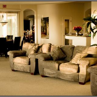 A cozy living room with a comfortable sofa and a view of the dining area in the background.