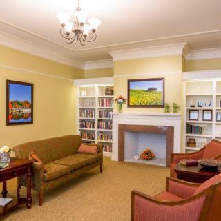 A cozy living room featuring traditional furniture, bookshelves, and a fireplace.